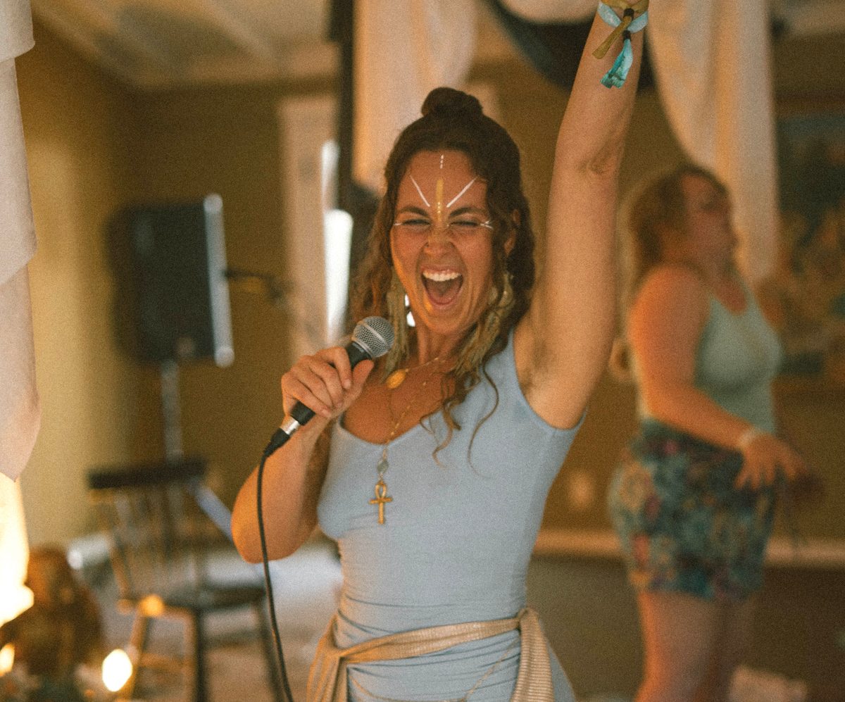 Damiana singing into a microphone, one arm raised
